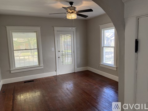 A room with a ceiling fan and wooden flooring.
