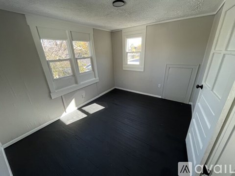 A room with white walls and a window with a view of trees.