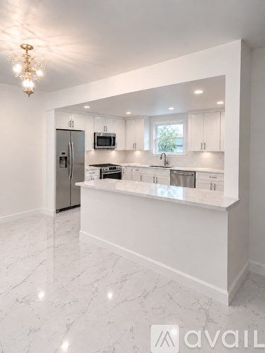 A kitchen with white cabinets and a marble countertop.