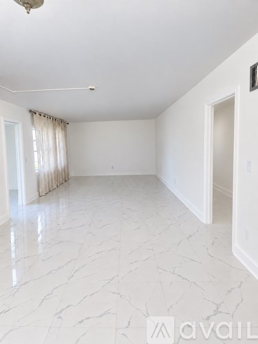 A spacious room with marble flooring and white walls.