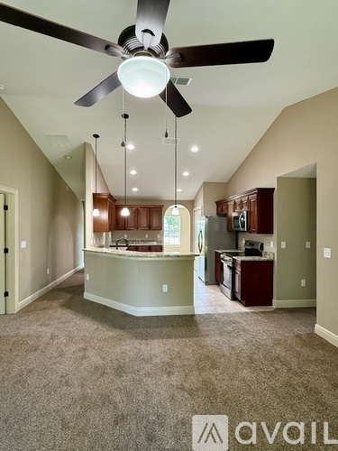 A spacious kitchen and living room with a ceiling fan and pendant lights.