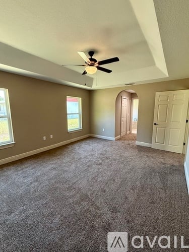A room with a ceiling fan and carpeted floor.