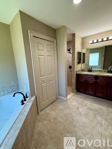 A bathroom with a tub, sink, and mirror.