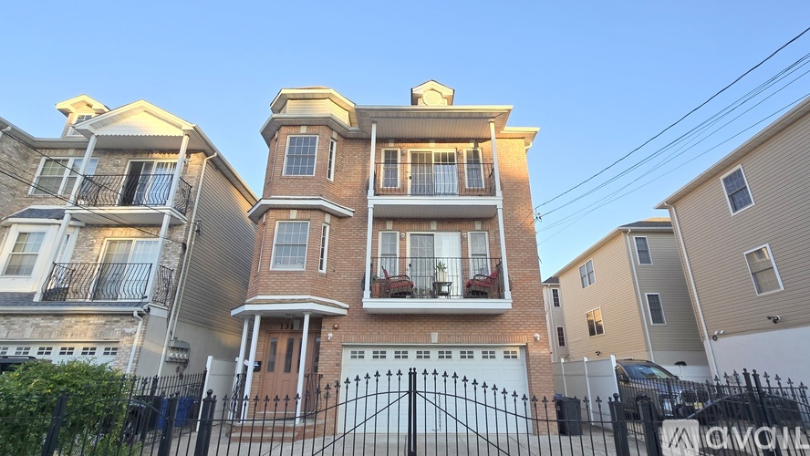 A large, two-story house with a black metal fence in front.