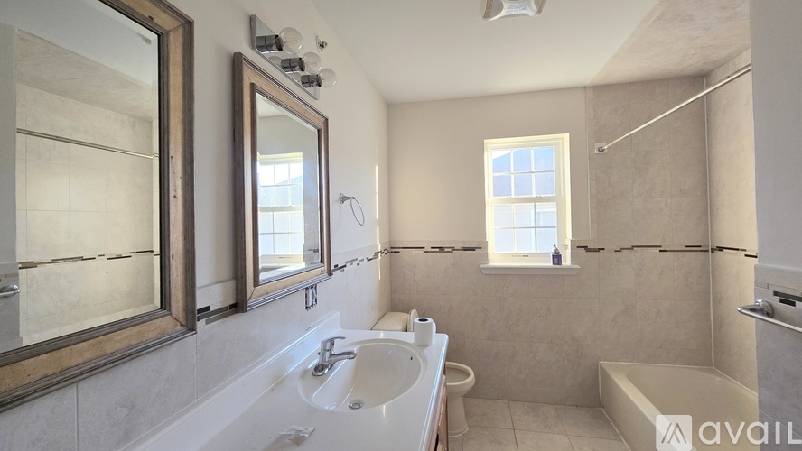 A bathroom with a large mirror, sink, and bathtub.