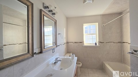 A bathroom with a large mirror, sink, and bathtub.