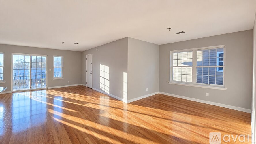 A spacious room with wooden floors and large windows.