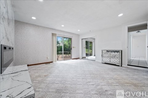 A spacious, empty room with a marble staircase and a large window with a view of trees.
