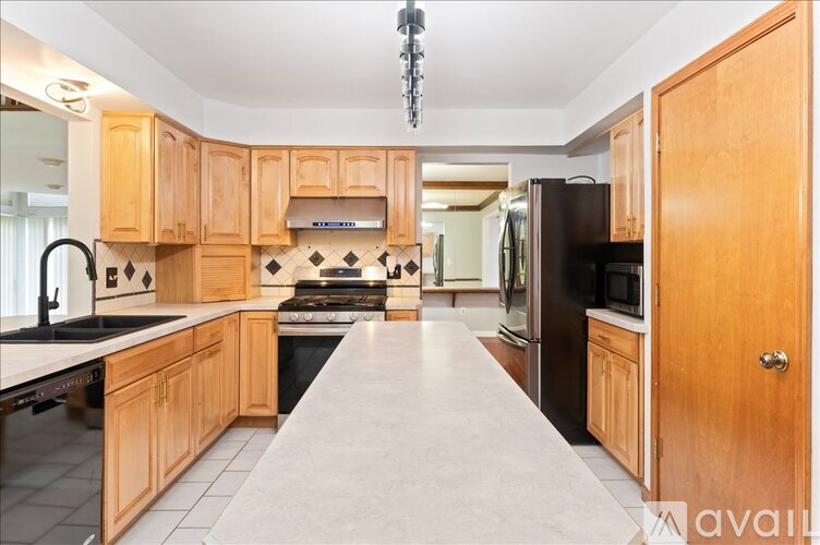 A kitchen with wooden cabinets and a long island in the middle.