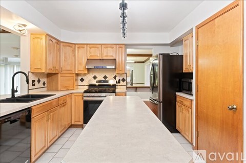 A kitchen with wooden cabinets and a long island in the middle.