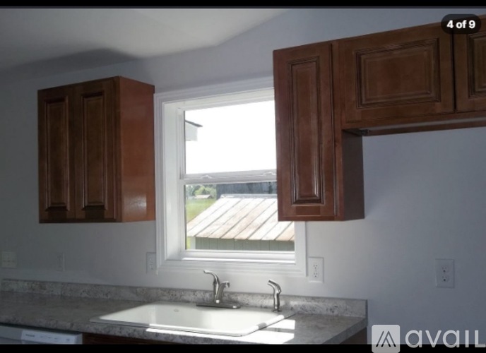 A kitchen with brown cabinets and a window overlooking a wooden deck.