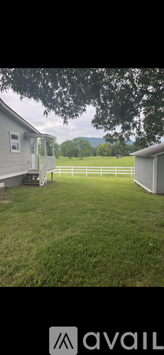 A grassy field with a fence and a house in the background.