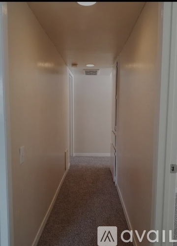 A long hallway with a carpeted floor and white walls.
