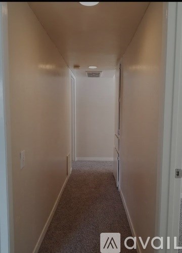 A long hallway with a carpeted floor and white walls.