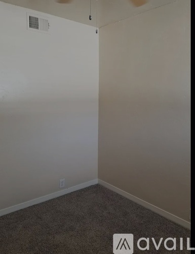 A room with a carpeted floor and a white wall.