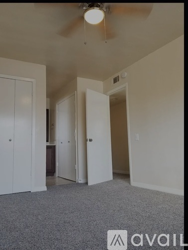 A room with a ceiling fan and carpeted floor.