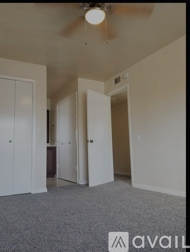 A room with a ceiling fan and carpeted floor.