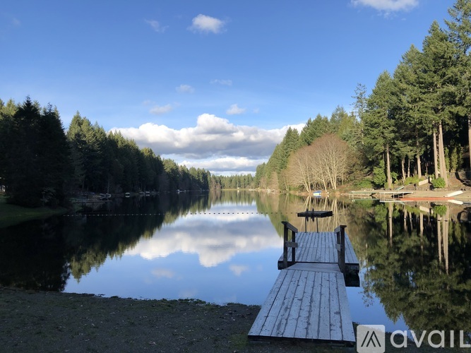 A dock extends into a calm lake surrounded by trees.