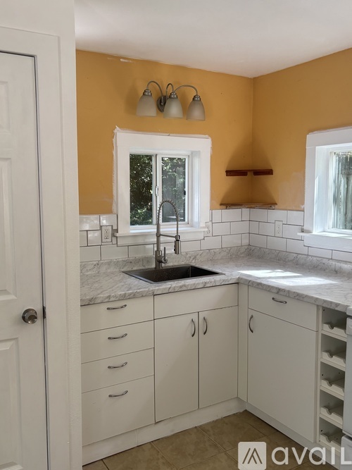 A kitchen with white cabinets and a marble countertop.
