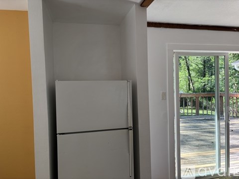 A white refrigerator in a room with a yellow wall.
