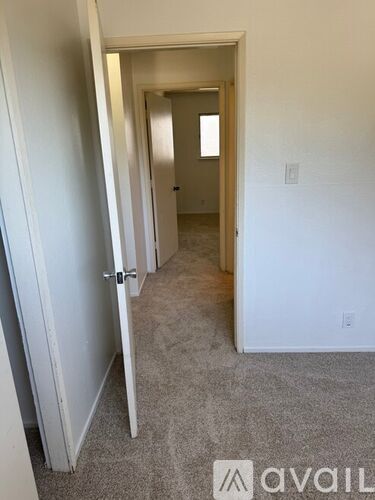 A hallway with a carpeted floor and white walls.