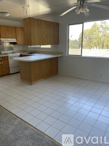 A kitchen with wooden cabinets and a white tile floor.