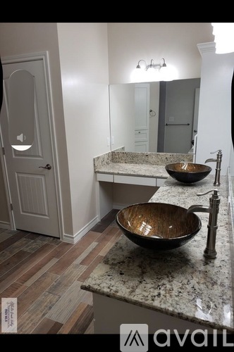 A bathroom with a marble countertop and a wooden bowl sink.