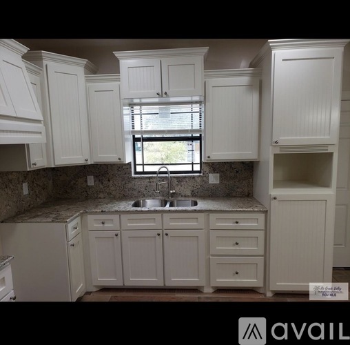 A kitchen with white cabinets and a granite countertop.