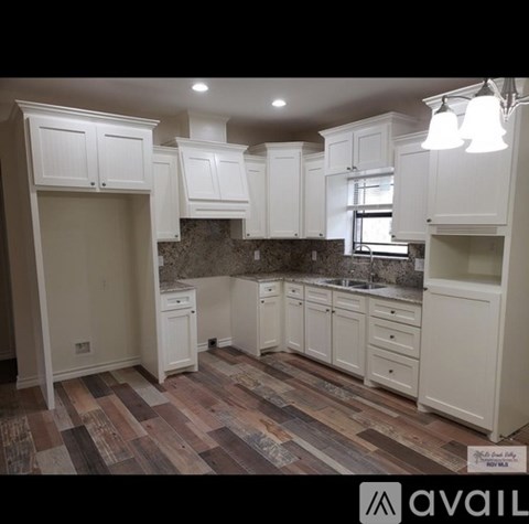 A kitchen with white cabinets and a wooden floor.