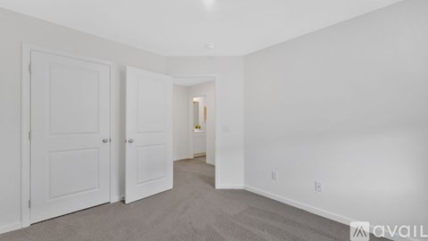 A room with white walls and carpeted floor with two doors.