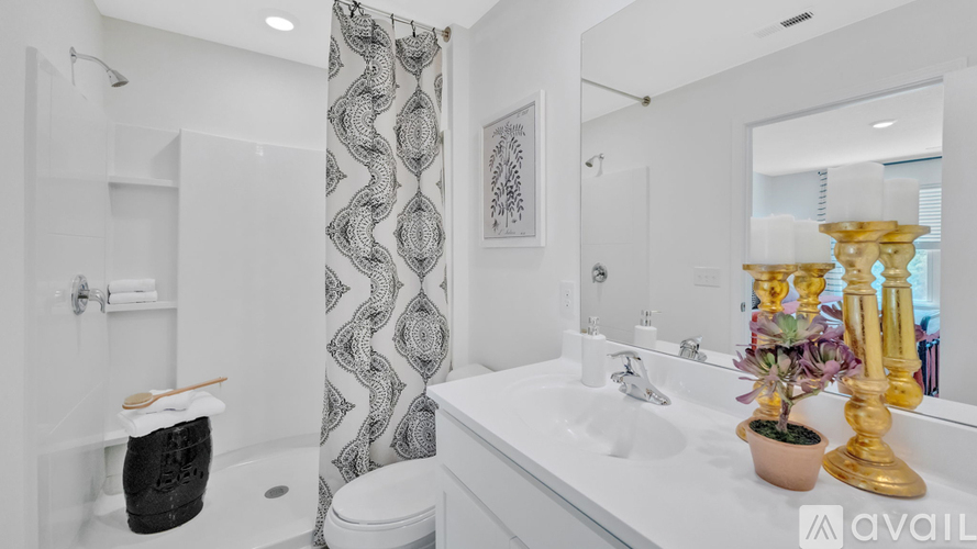 A bathroom with a white sink, gold faucet, and a shower with a black and white curtain.