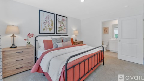 A bedroom with a red bed, two lamps, and two framed pictures on the wall.