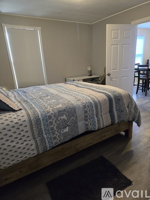 A bedroom with a bed, desk, chair, and window.