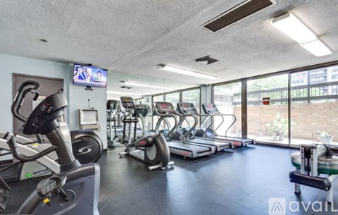 A gym with treadmills, exercise bikes, and a television.
