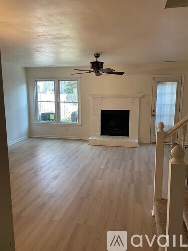 A living room with a fireplace and a ceiling fan.