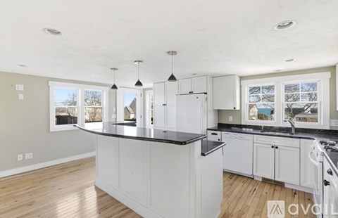 A kitchen with white cabinets and a black countertop.