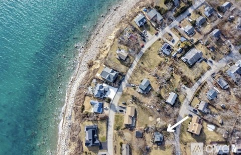 A bird's eye view of a coastal residential area with houses and roads.