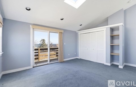 A spacious room with a skylight and a sliding glass door leading to a deck.