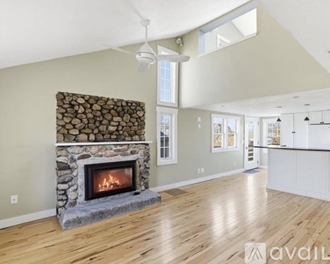 A living room with a stone fireplace and wooden floors.
