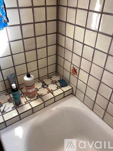 A bathroom with a white tub and tiled walls.