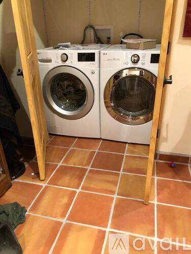 Two washing machines are in a small laundry room.