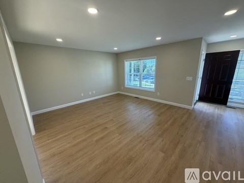 A room with wooden flooring and a window with blinds.