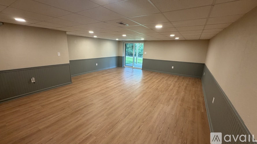 A spacious room with wooden flooring and a large window.