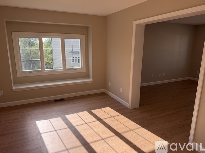 A room with a large window and wooden flooring is available for rent.