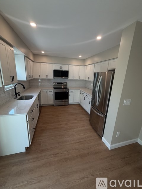 A kitchen with white cabinets and a wooden floor.