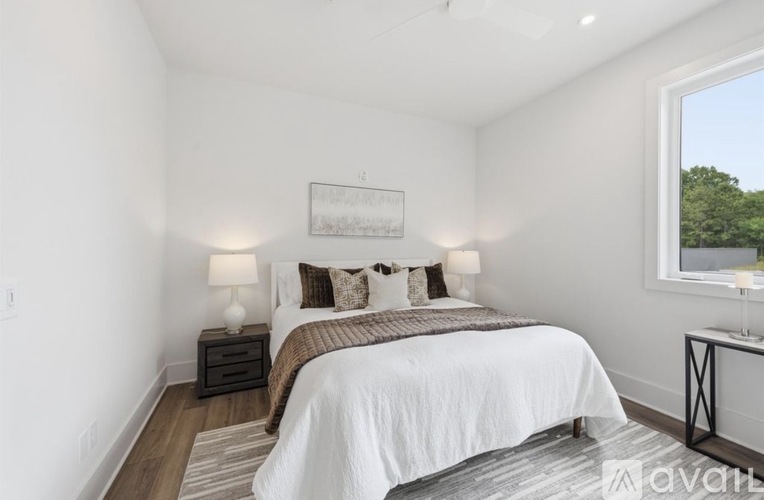 A bedroom with a large bed and a window overlooking trees.