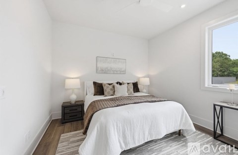 A bedroom with a large bed and a window overlooking trees.