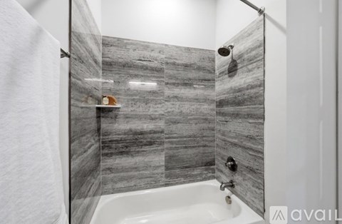 A bathroom with a marble tile shower and a white bathtub.