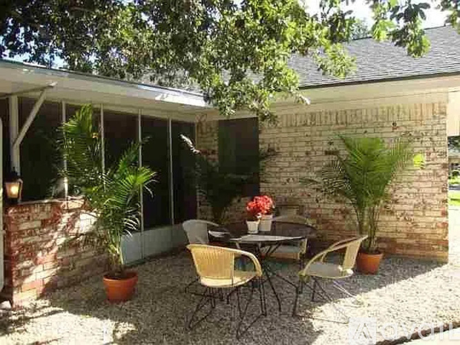 A patio with a table and chairs is surrounded by a gravel area.