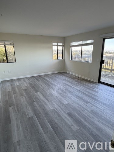 A spacious room with grey flooring and large windows.